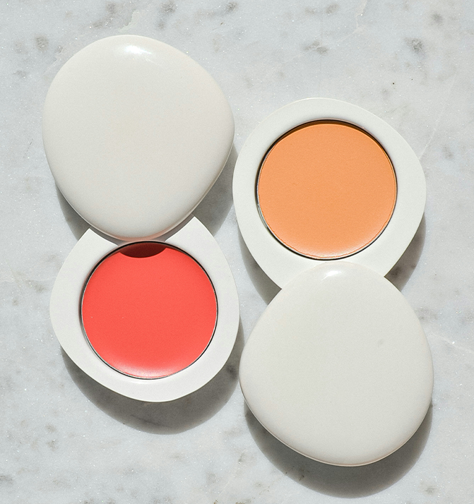 Two makeup products with coral and peach shades on a marble surface