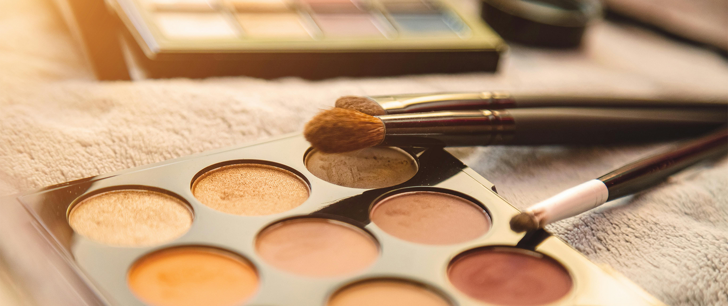 Makeup palette with eyeshadows and brushes on a textured surface